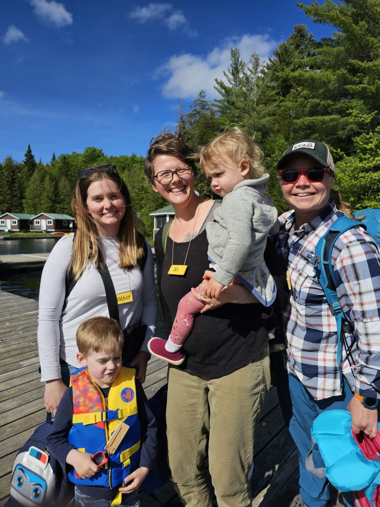 A group of five people pose for a photo on a lakeside dock