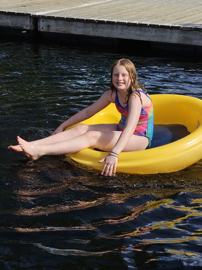 A child sits in an inflatable ring in a lake