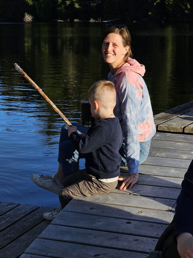A woman and a child sit on the edge of a dock fishing