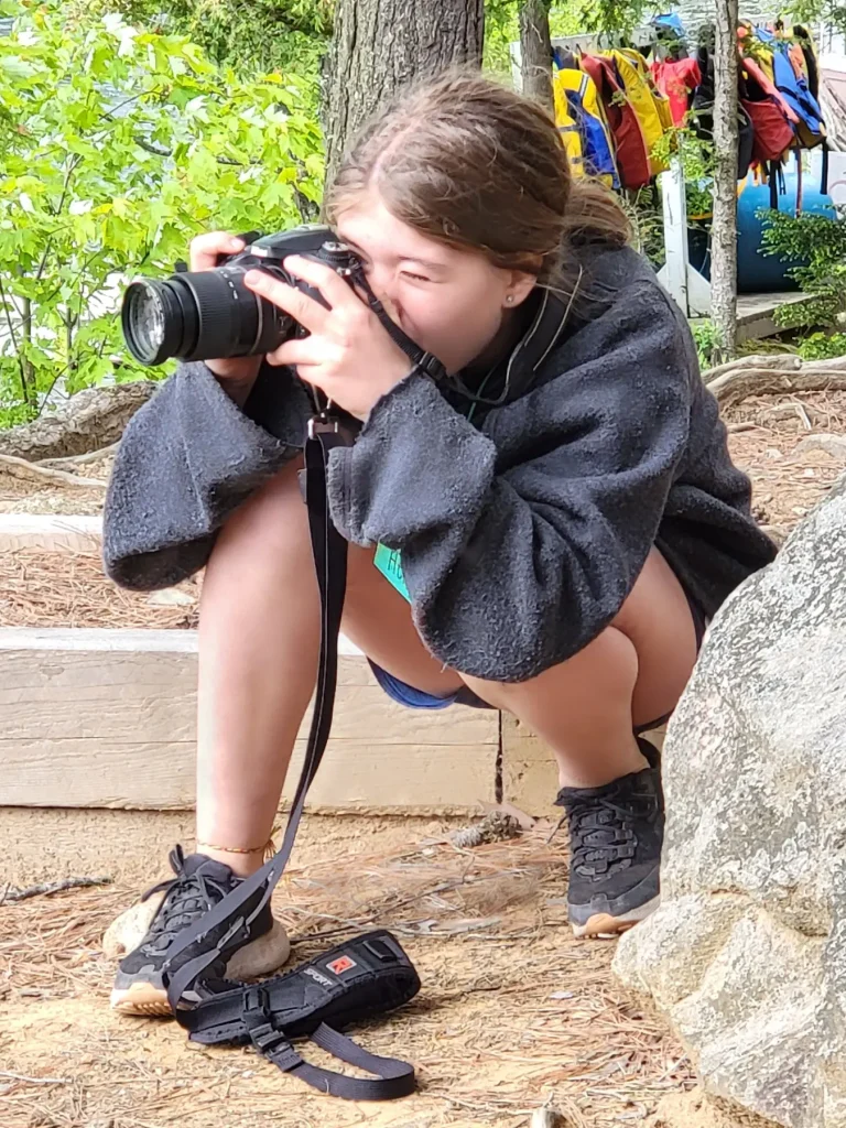 A young person drops low and leans in with a camera