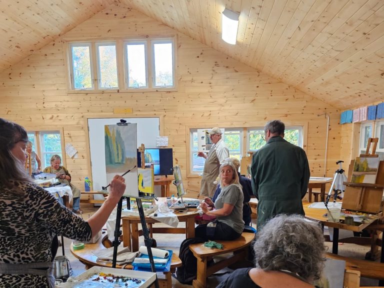 A group of people painting in a large room with a sloped roof