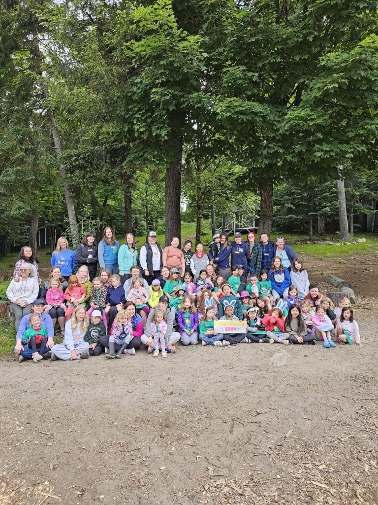 Children and adults gather outdoors for a large group photo