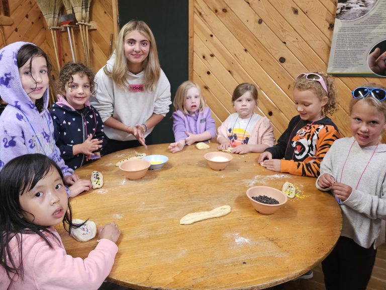Children and an adult facilitator sit around a wooden table