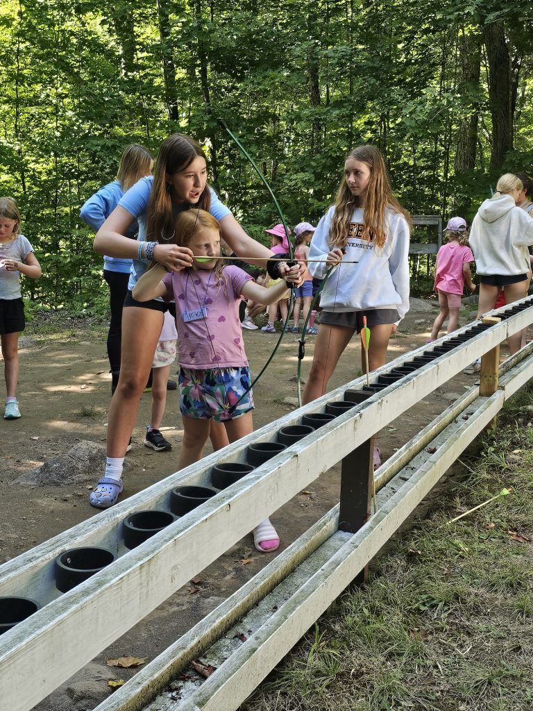 A counsellor adjust a young archer's aim