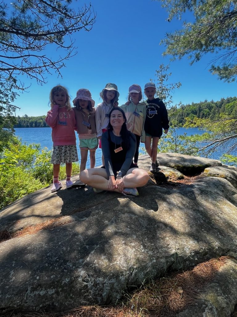 Five children and one adult pose on a rock outcropping