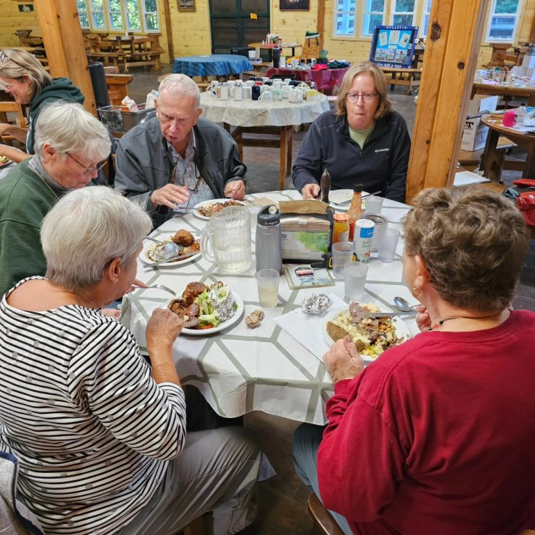 A group of five older people around a table for a meal