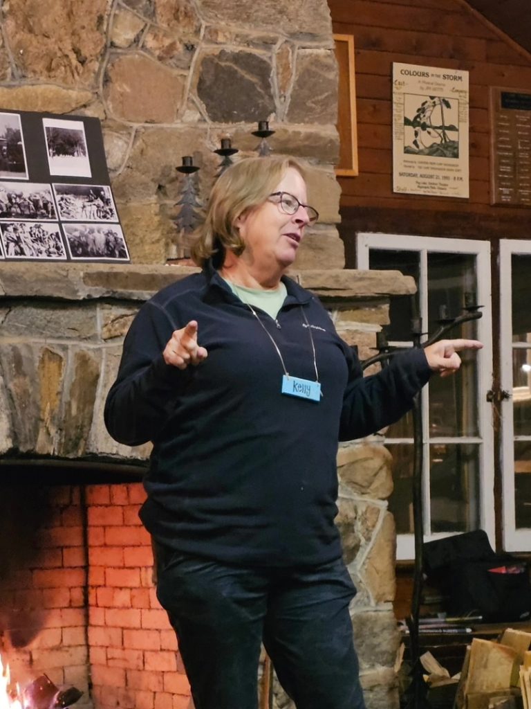 A person speaking in front of a stone fireplace