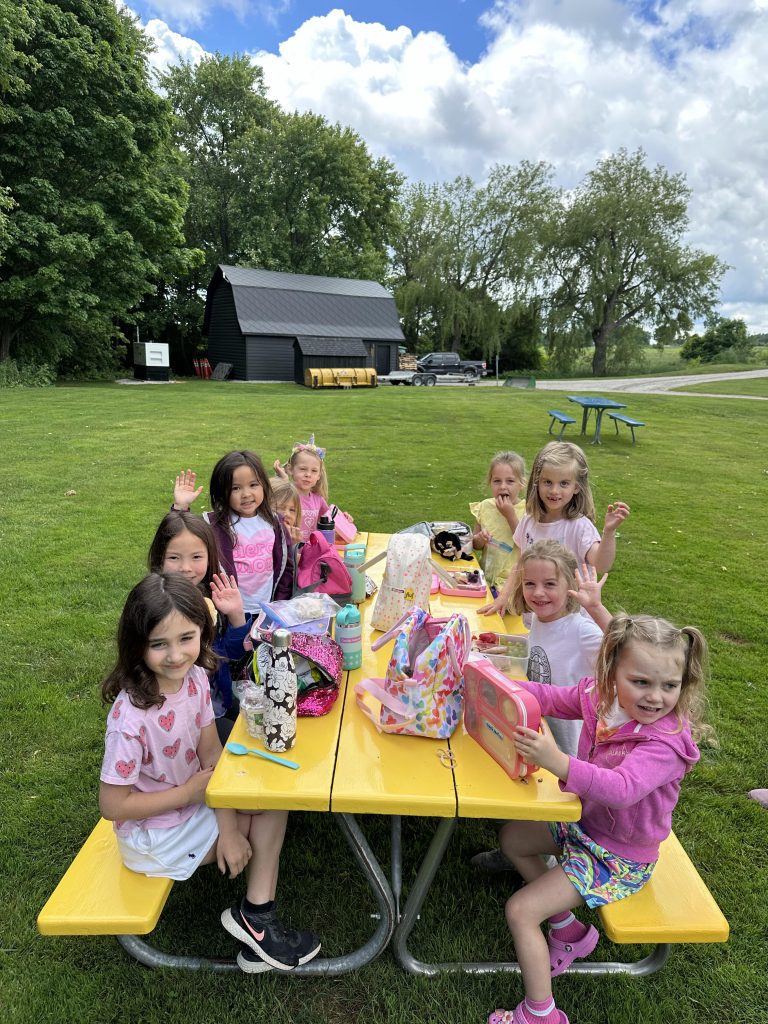 A group of smiling children at a yellow picnic table