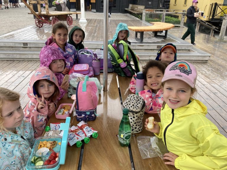 Kids in rain slickers sit around a picnic table