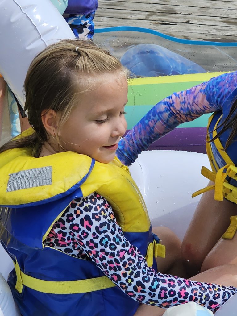 A girl in a yellow and blue life preserver