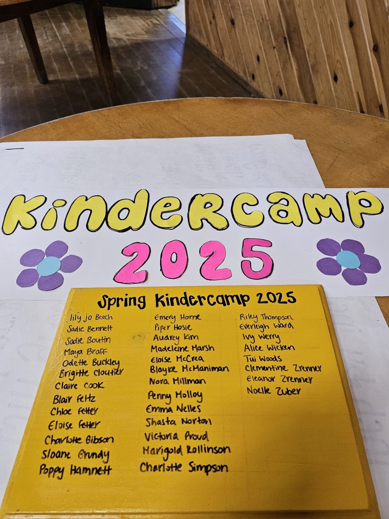 A yellow and pink sheet reading "Kindercamp 2025"