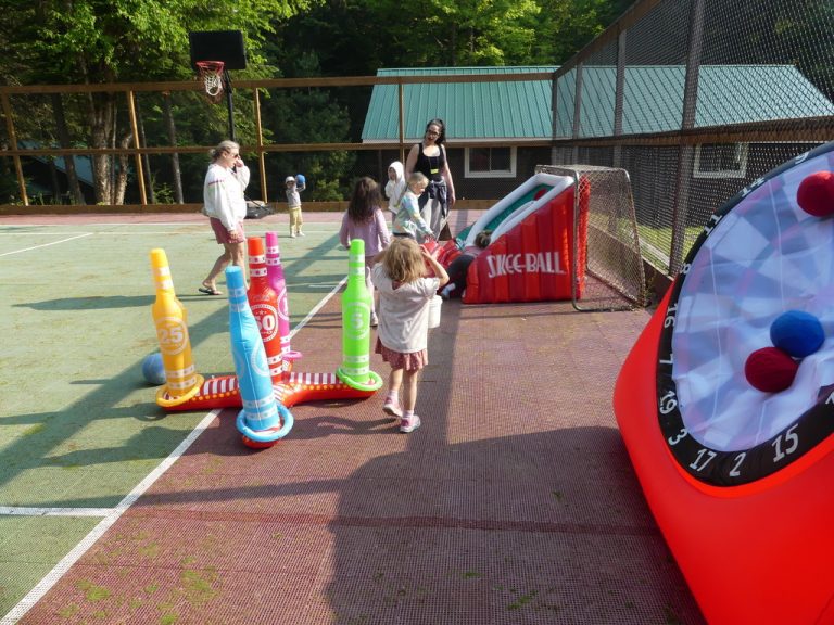 People on a tennis court, with a prominent inflatable ring toss game nearby