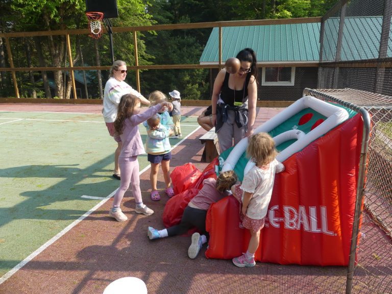 Children and adults gather around an inflatable ball toss game