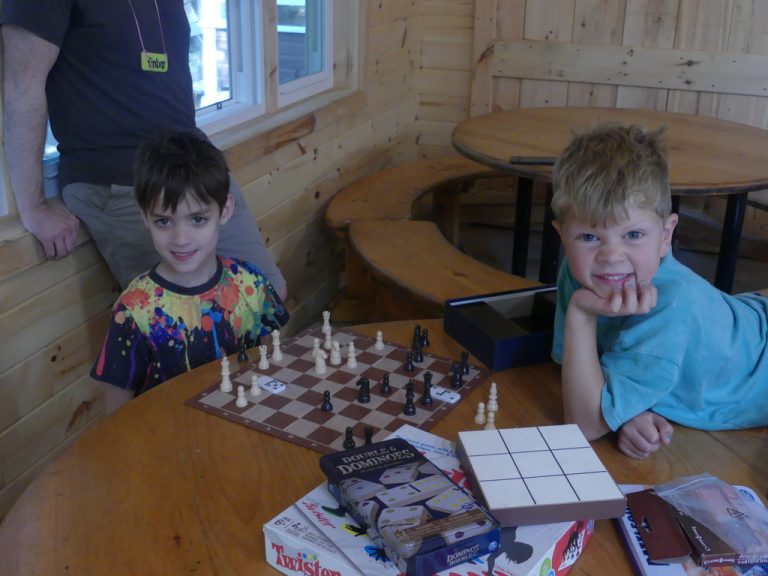 Two kids sit at a chess board