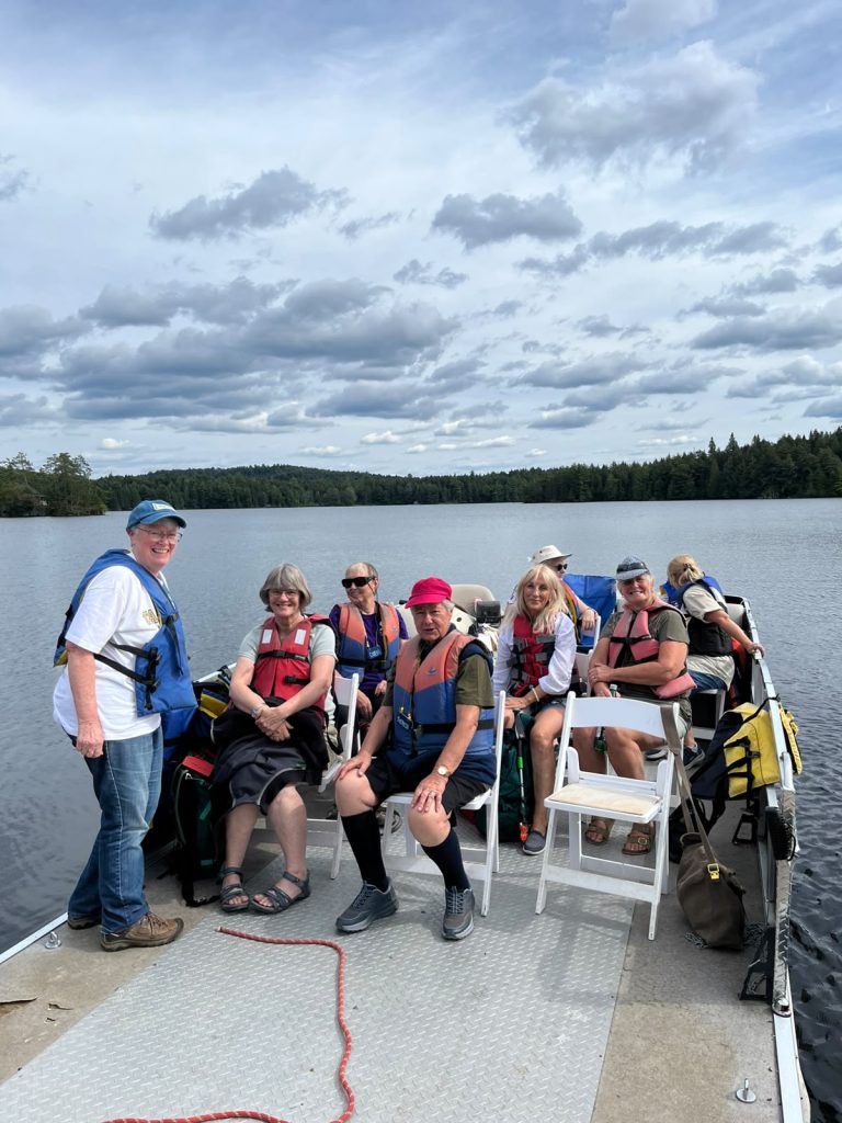 A group of people post for a photo on a pontoon boat on a lake