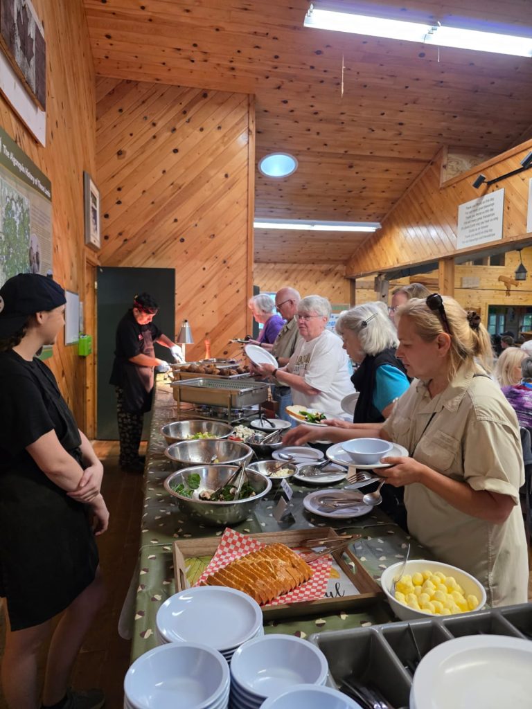 People line up for a buffet in a wood-panelled room