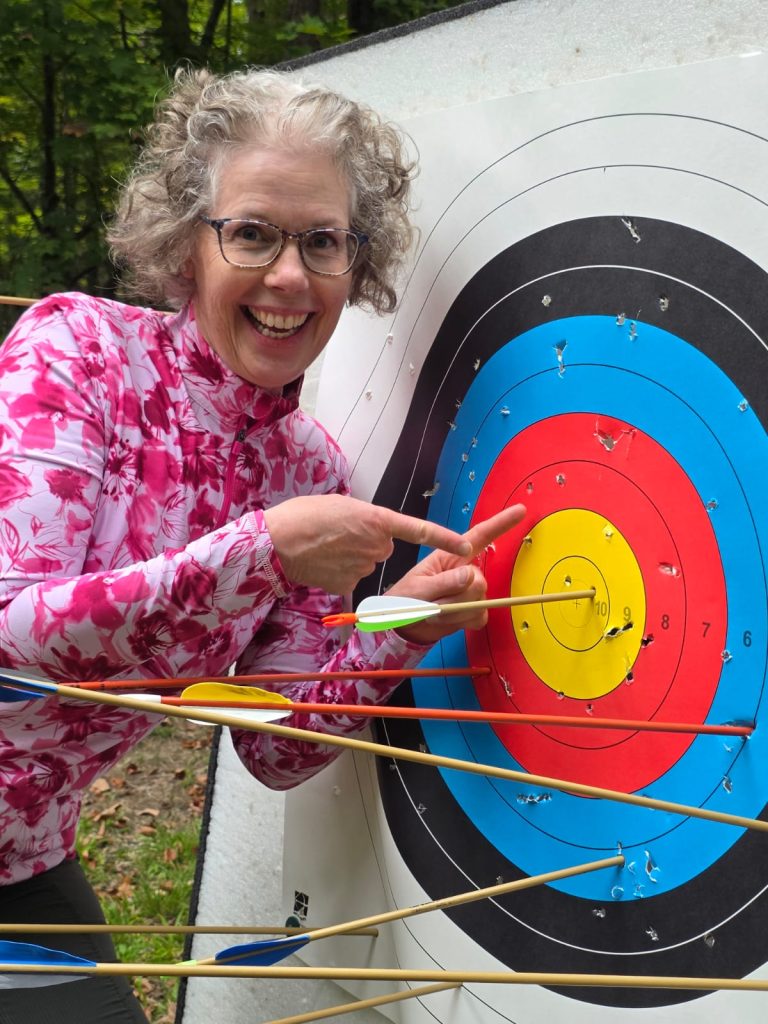 A woman points excitedly towards an archery target